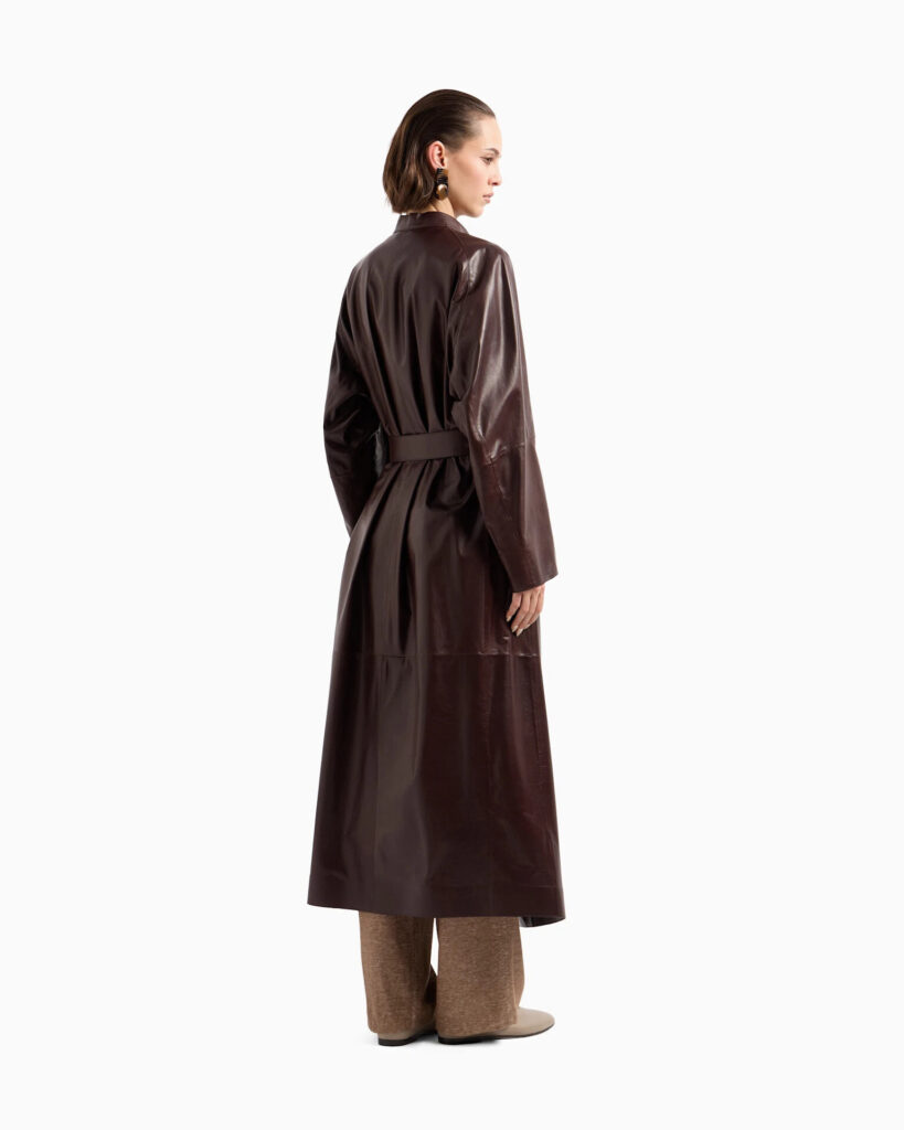 Full-length taupe leather coat with fur lining and sash belt on a wooden hanger