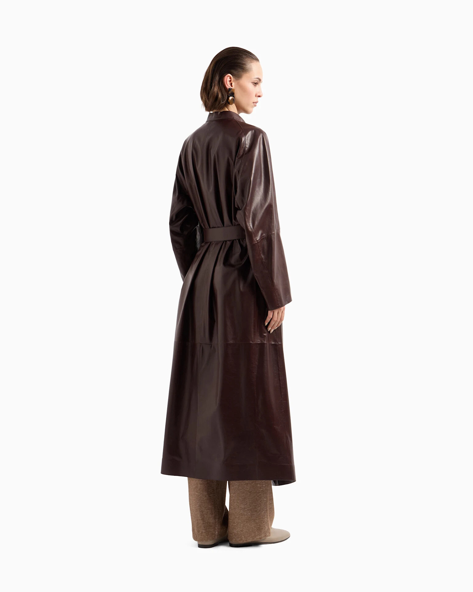 Full-length taupe leather coat with fur lining and sash belt on a wooden hanger