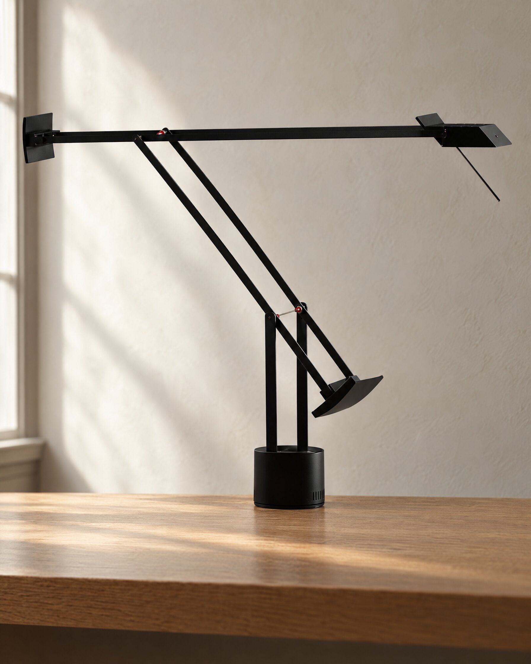 Artemide Tizio 50 table lamp in black with arms fully extended on an oak desk