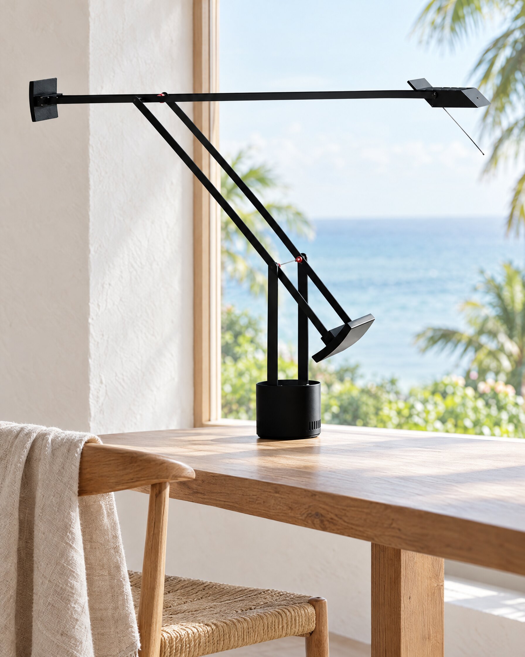 Black articulated desk lamp on a table beside a sea-view window in a quiet villa interior