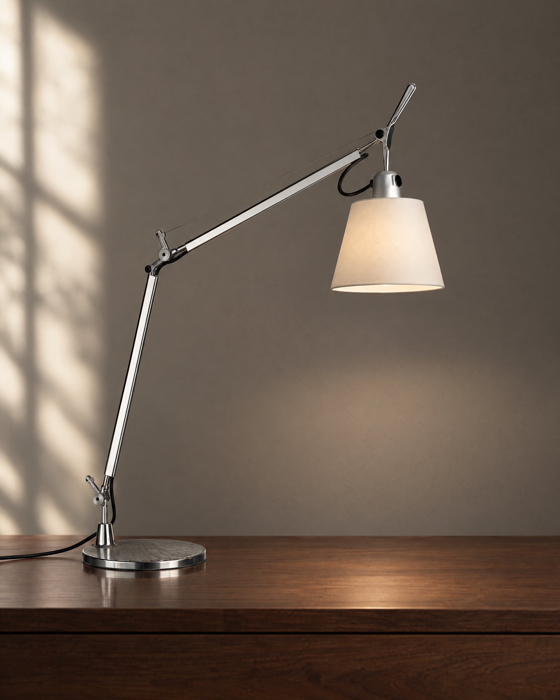 Artemide Tolomeo Basculante Tavolo table lamp with parchment diffuser and aluminium arm on a walnut surface