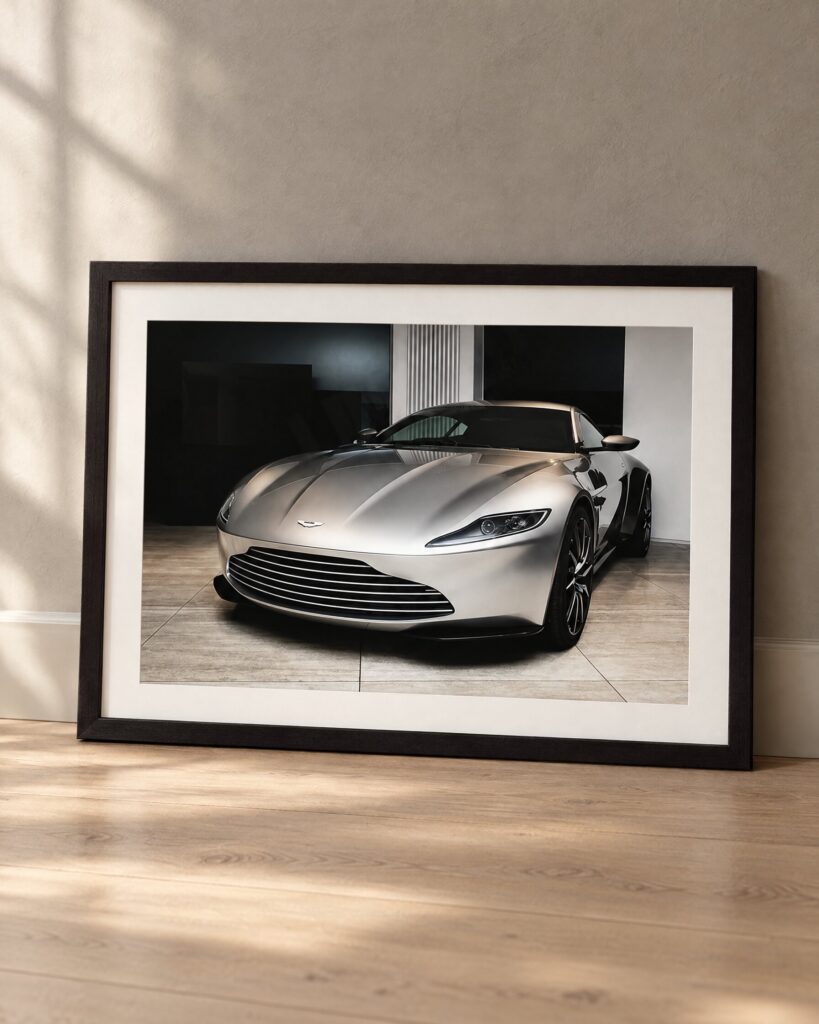 Framed Aston Martin DB10 print leaning against a grey plaster wall