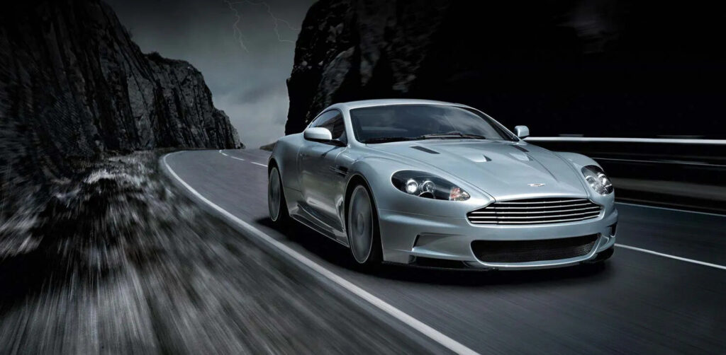 Dark grey Aston Martin DBS Quantum of Solace car parked on a quiet Italian lakeside road at dawn