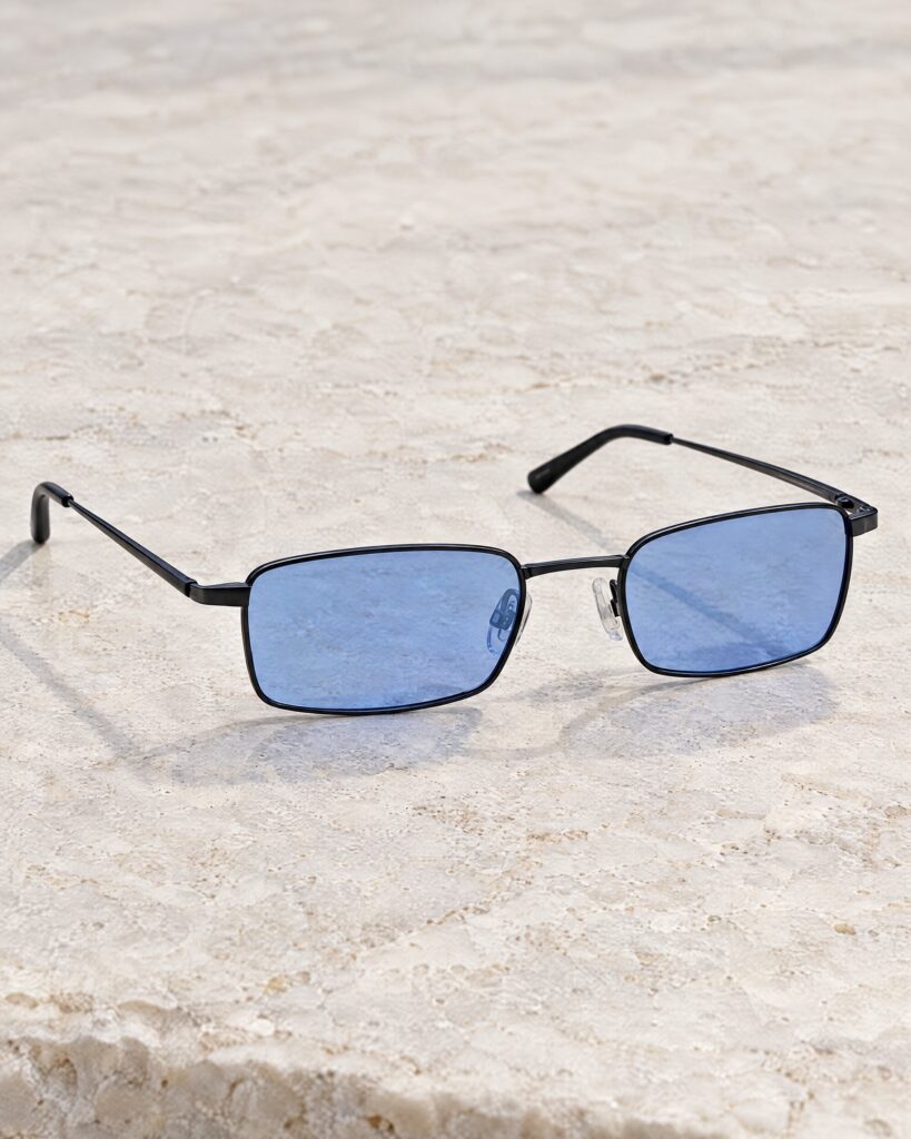 Bond X-ray glasses style small black metal frames with pale blue lenses on stone