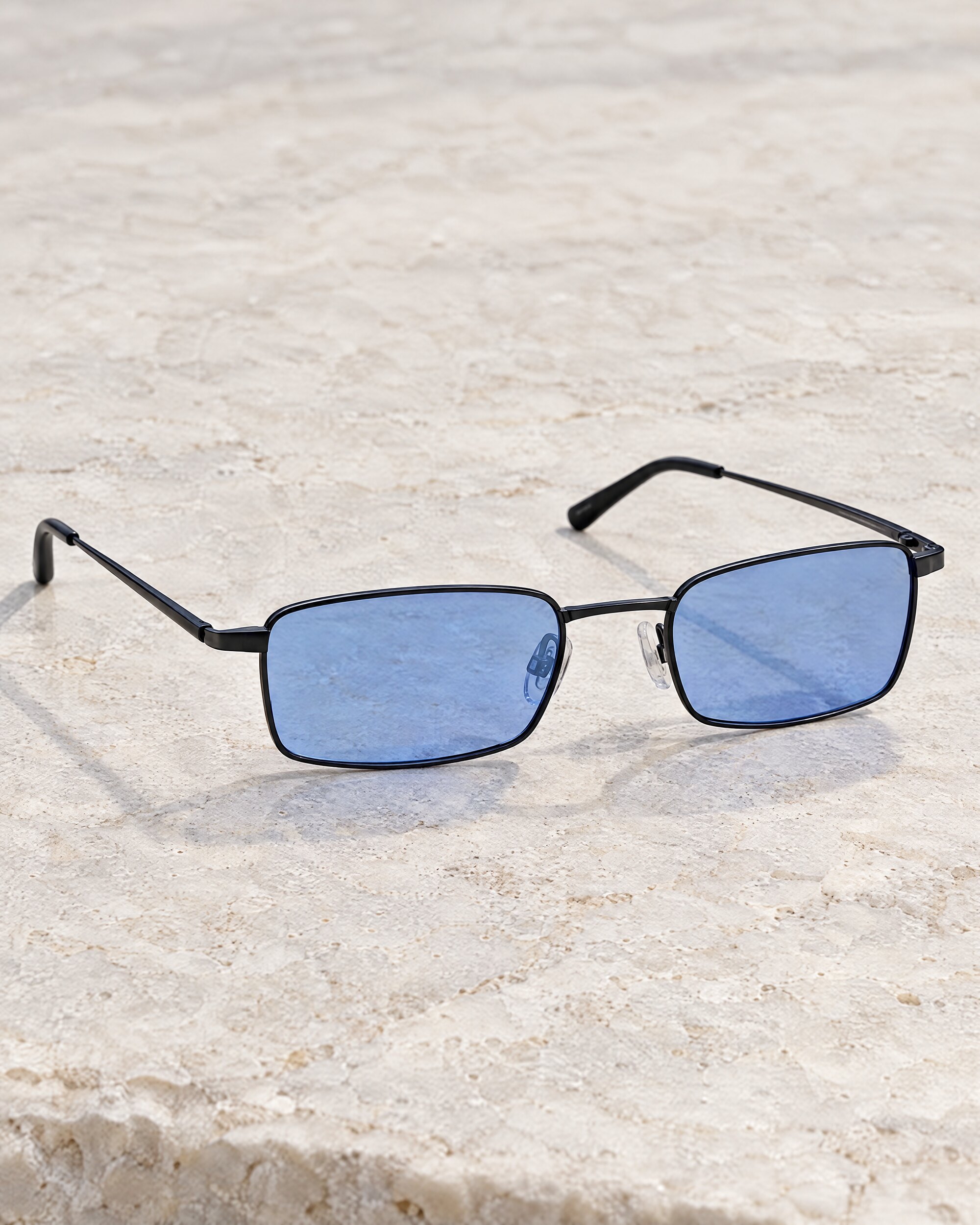Bond X-ray glasses style small black metal frames with pale blue lenses on stone