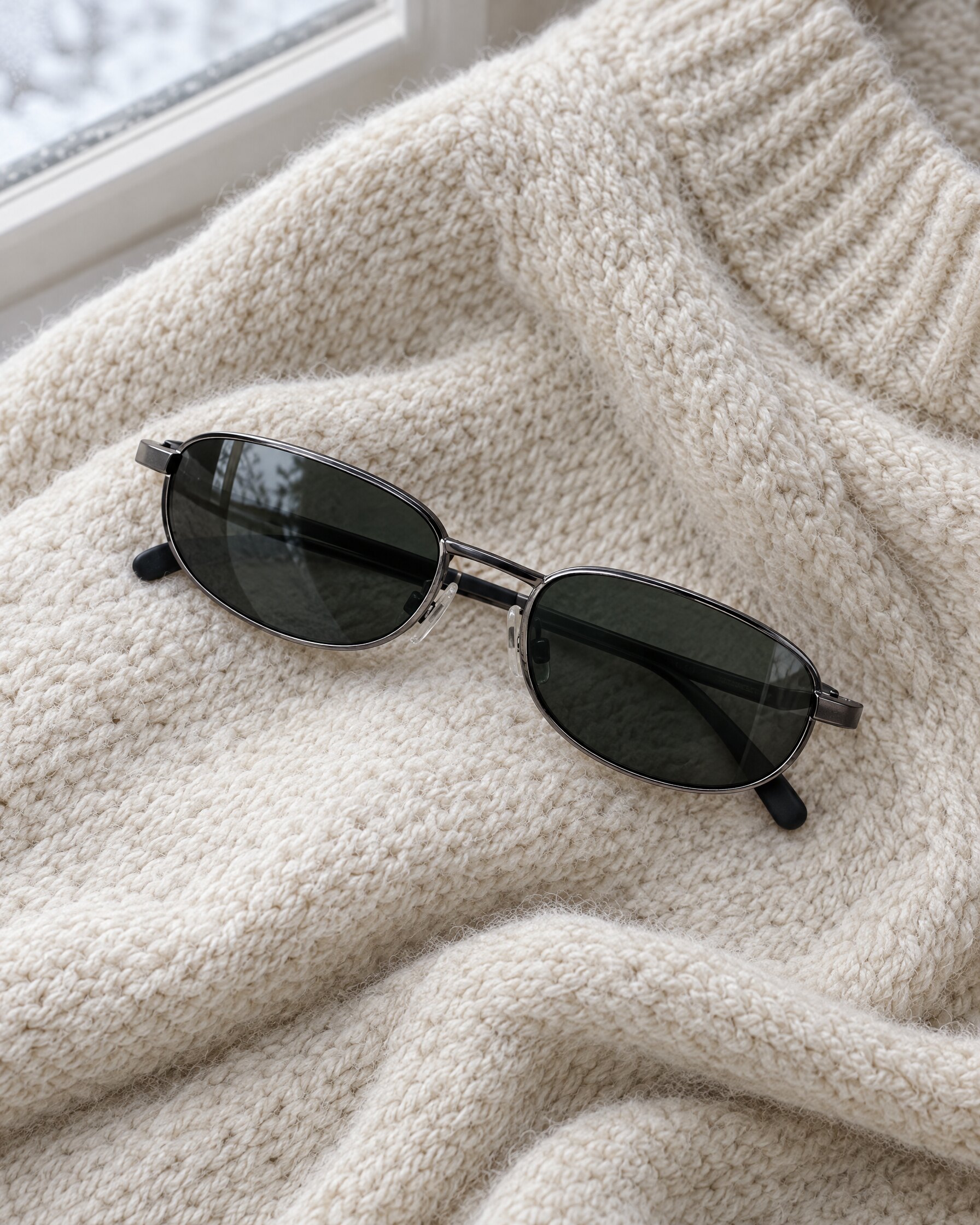 Calvin Klein 2007 style dark sunglasses resting on a wool sweater