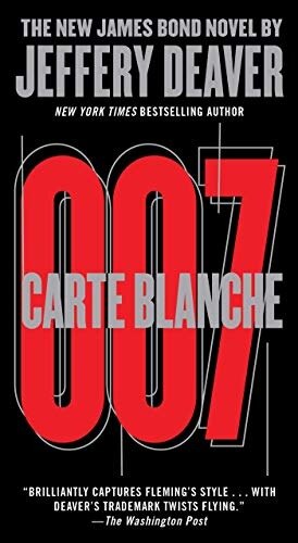 Closed hardback novel on a walnut desk beside a brass paperweight, for Carte Blanche by Jeffery Deaver
