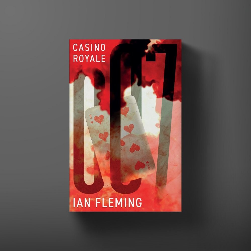 Closed red hardback novel on a green baize card table beside a martini