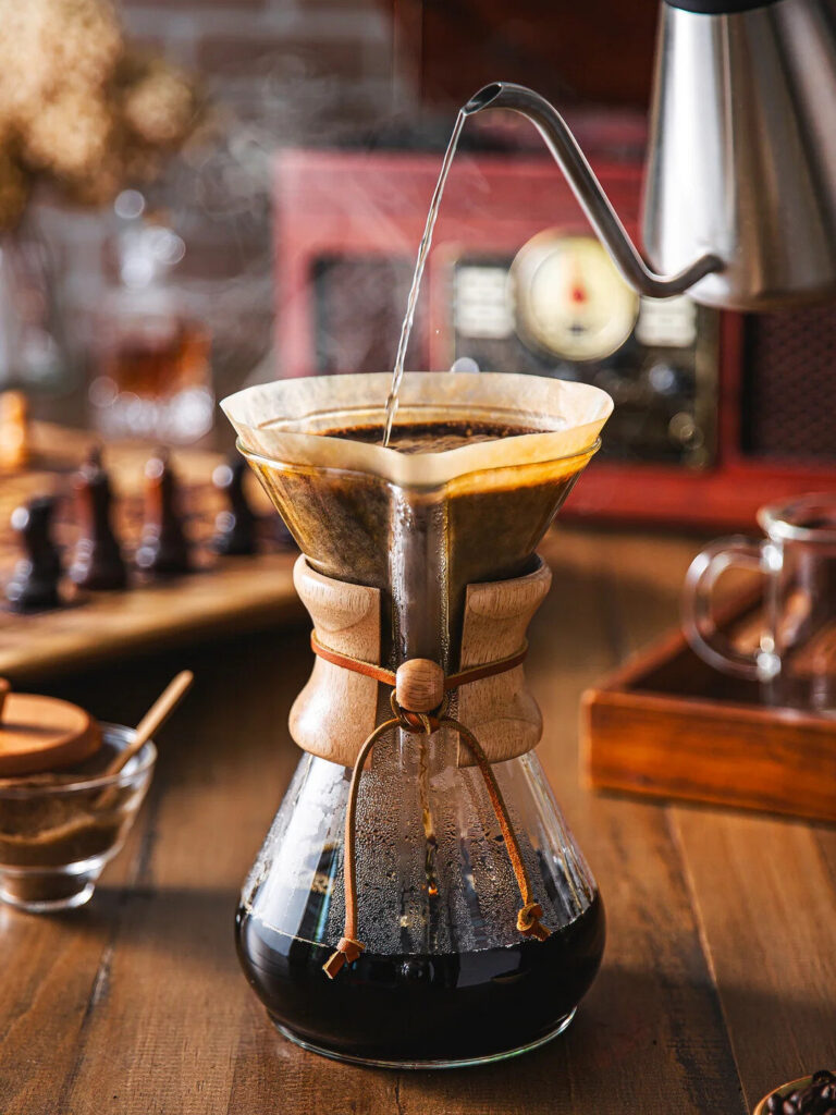Hourglass glass coffeemaker with wooden collar on white linen