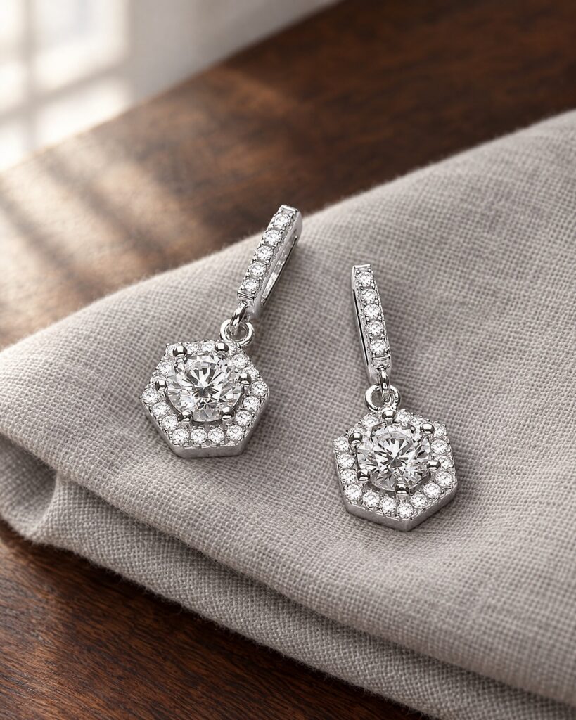 David Deyong Spectre earrings, hexagon drop earrings in rhodium-plated sterling silver with Swarovski Zirconia, on grey linen