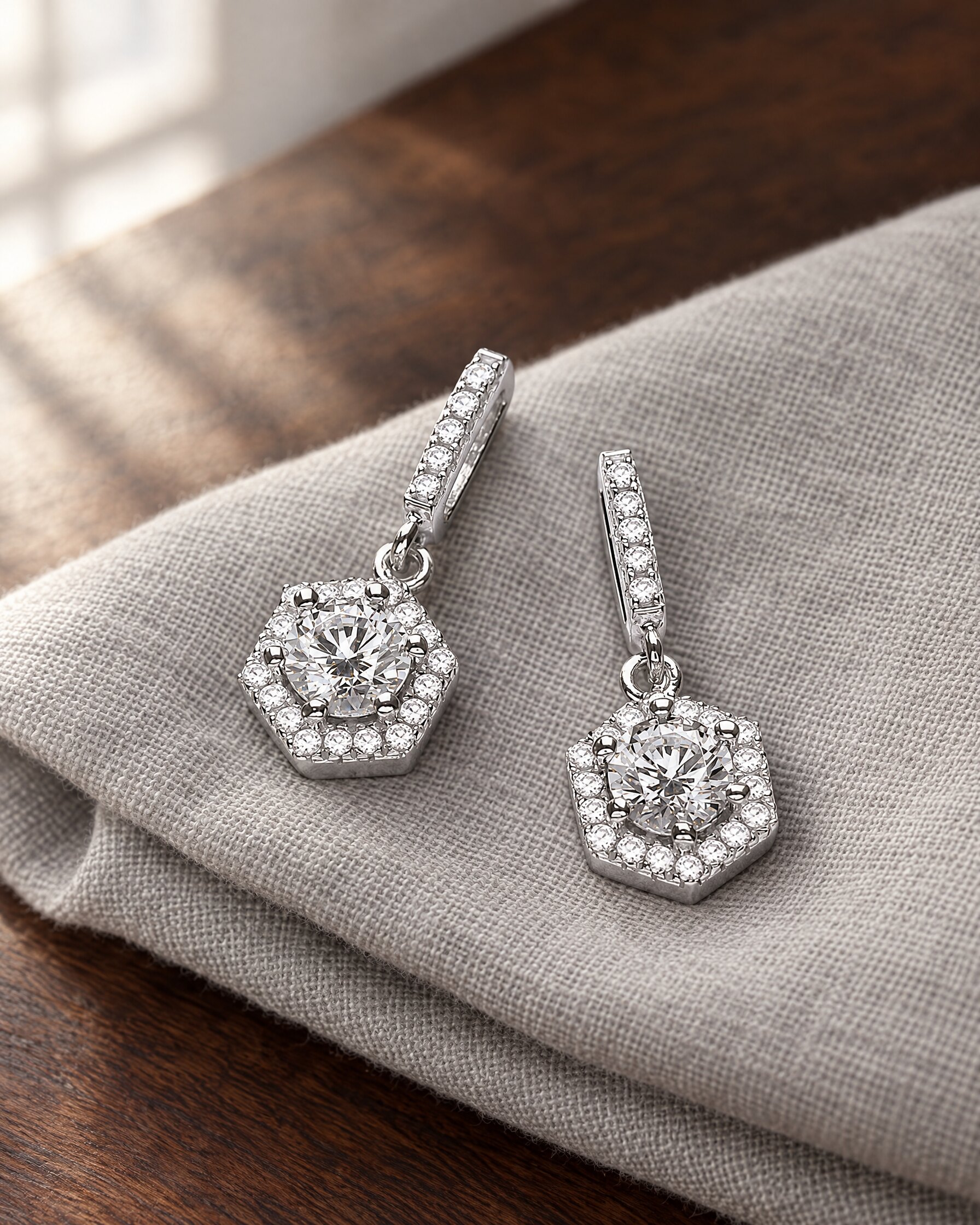 David Deyong Spectre earrings, hexagon drop earrings in rhodium-plated sterling silver with Swarovski Zirconia, on grey linen