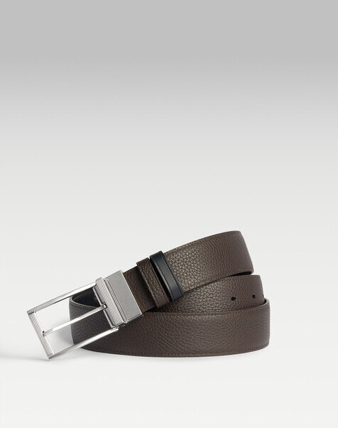 Plain dark brown leather belt coiled beside brown shoes and a navy jumper