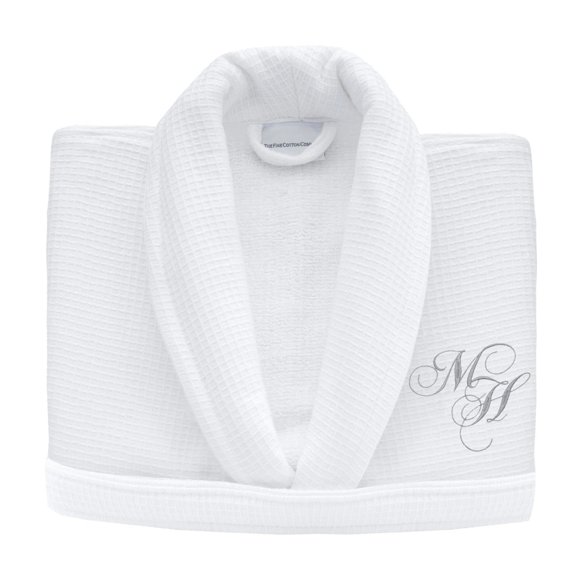 Folded cotton bath towels with a dark green border on an oak bench, in the style of a Fine Cotton Company embroidered towel