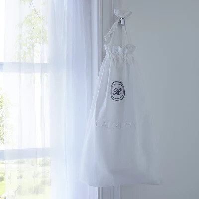 Green embroidered cotton drawstring laundry bag on an oak floor, in the spirit of the Spectre laundry bag