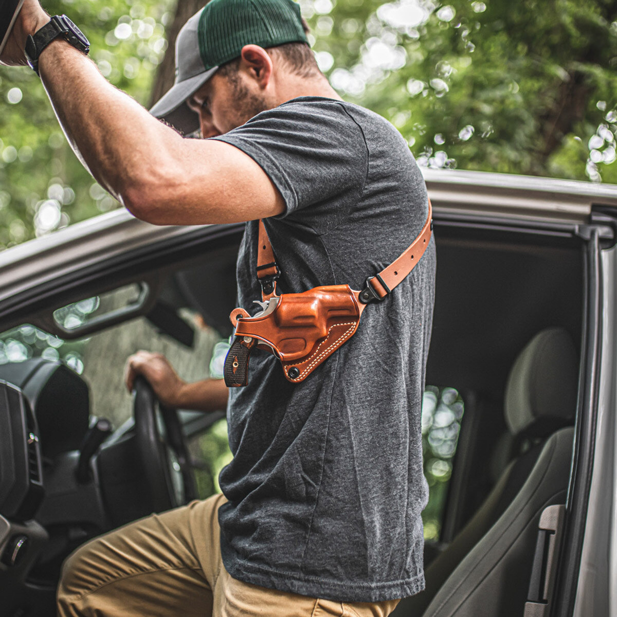 Black leather shoulder holster harness laid flat on a wooden table