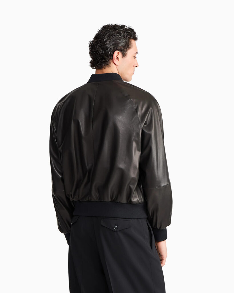 Brown Giorgio Armani leather jacket from Casino Royale laid flat with a navy knit and suede boots