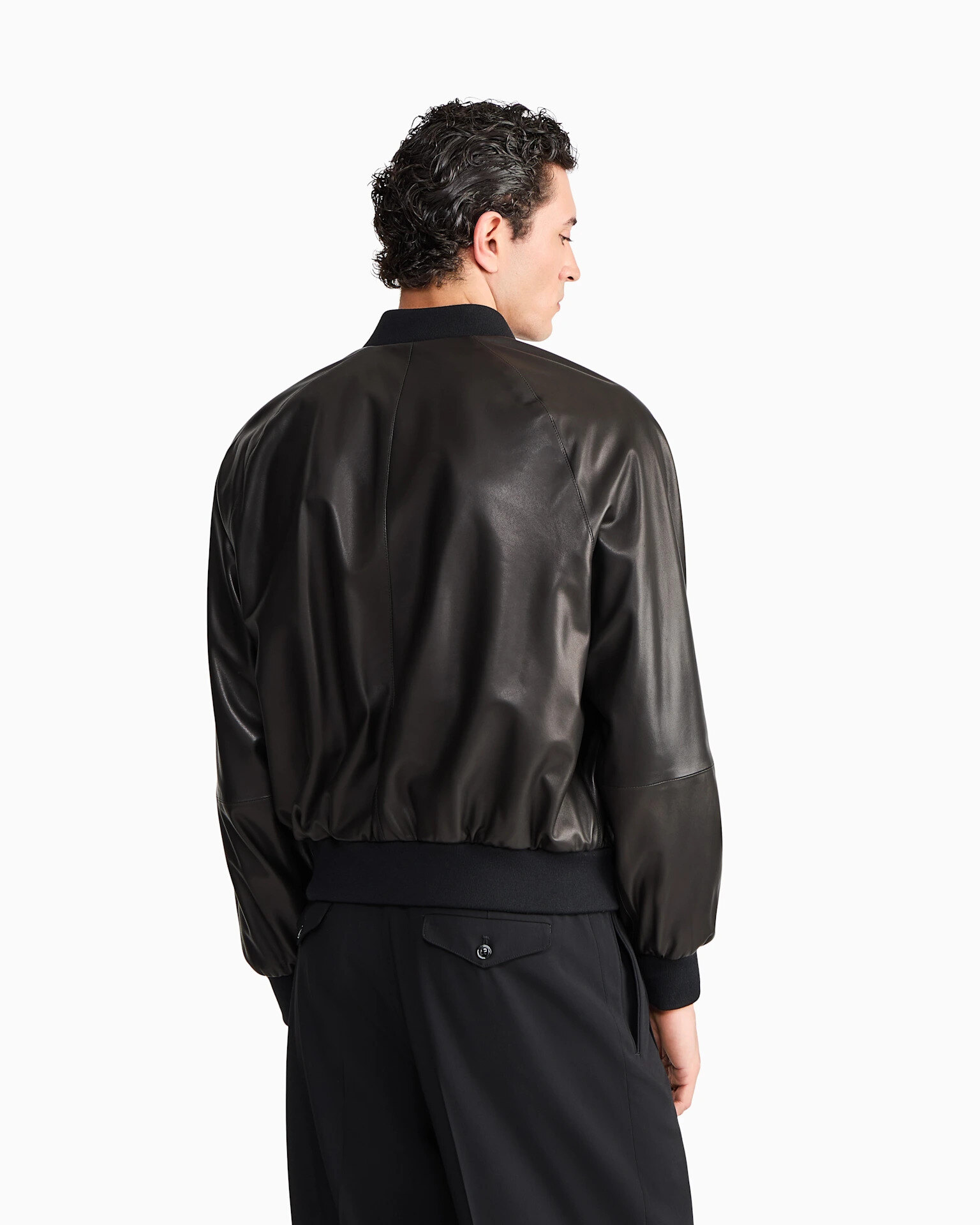Brown Giorgio Armani leather jacket from Casino Royale laid flat with a navy knit and suede boots