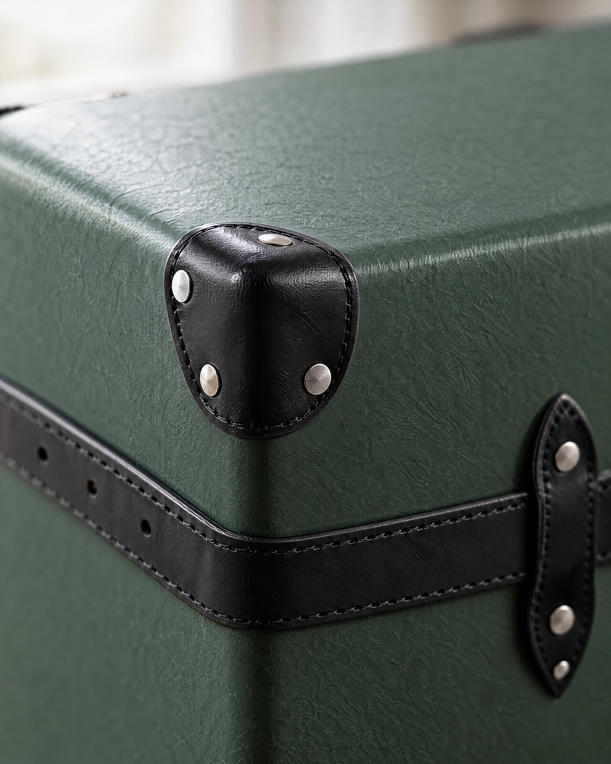 Close detail of black leather corner and green vulcanised fibreboard on a Globe-Trotter check-in case