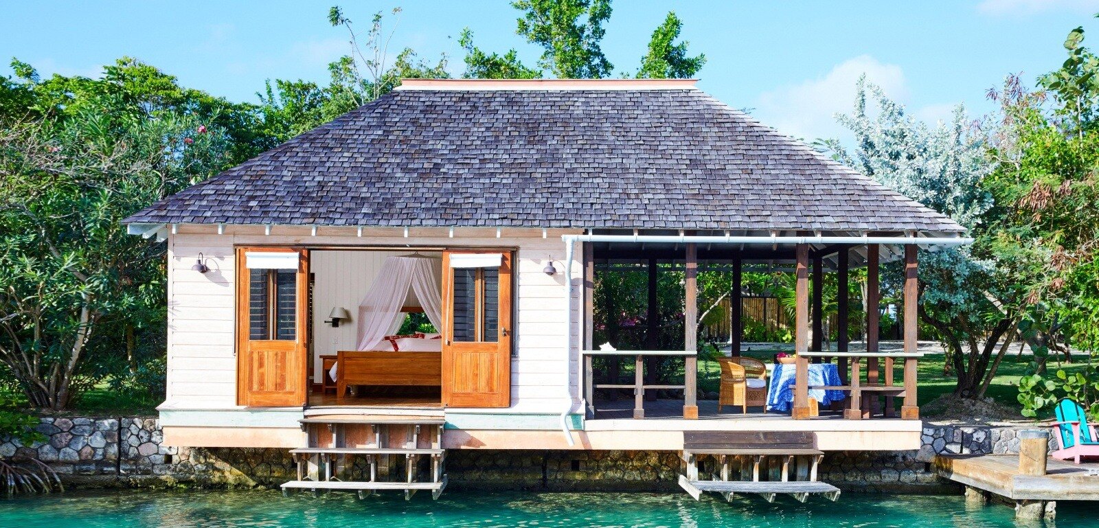 Whitewashed villa above a private cove in a tropical garden, in the spirit of GoldenEye Jamaica