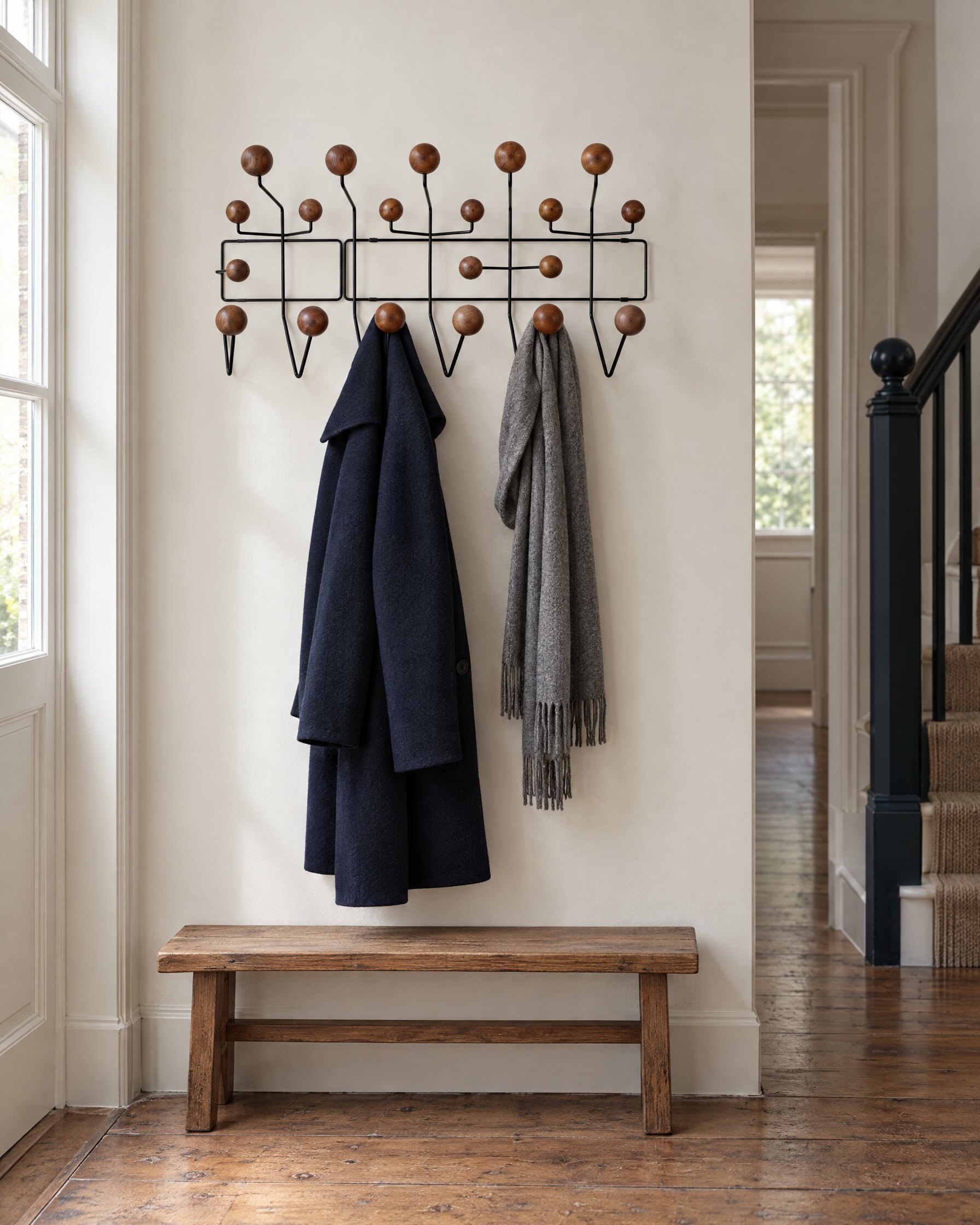 Navy overcoat hung on a wall-mounted rack in a quiet hallway