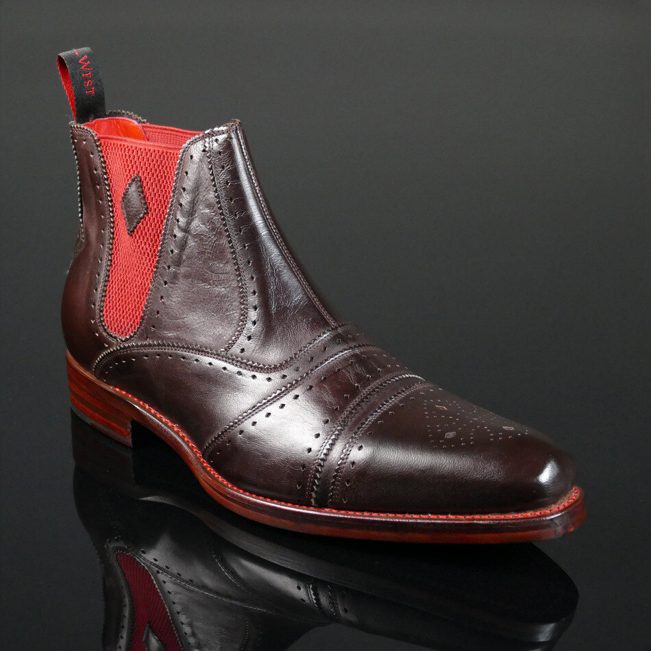 Brown brogue Chelsea boots with red lining on a stone floor