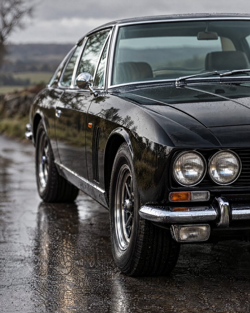Black Jensen Interceptor FF front wing and headlamps on a wet country road