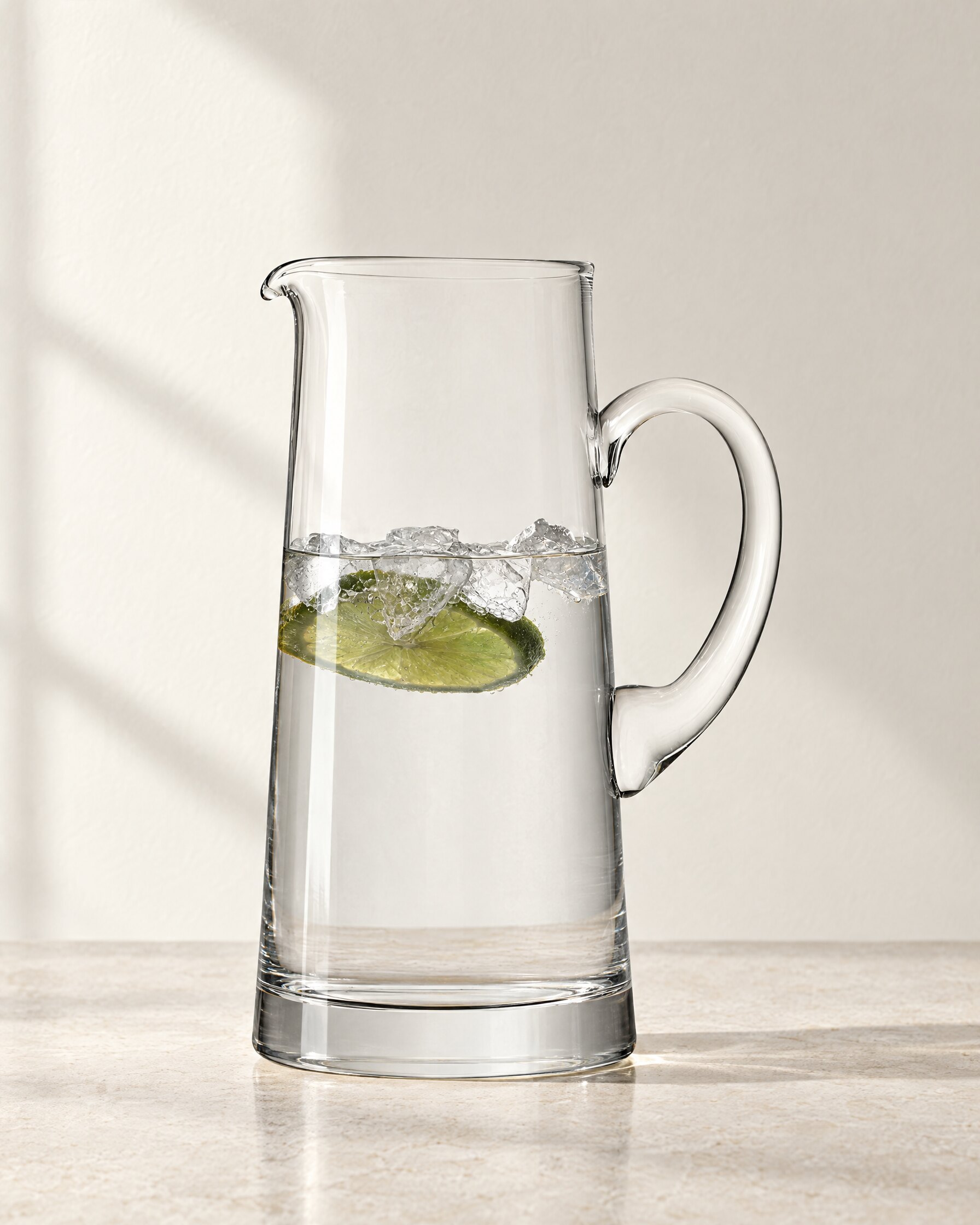 LSA Bar Tapered Jug in clear mouth-blown glass, filled with water, ice and lime on a stone surface