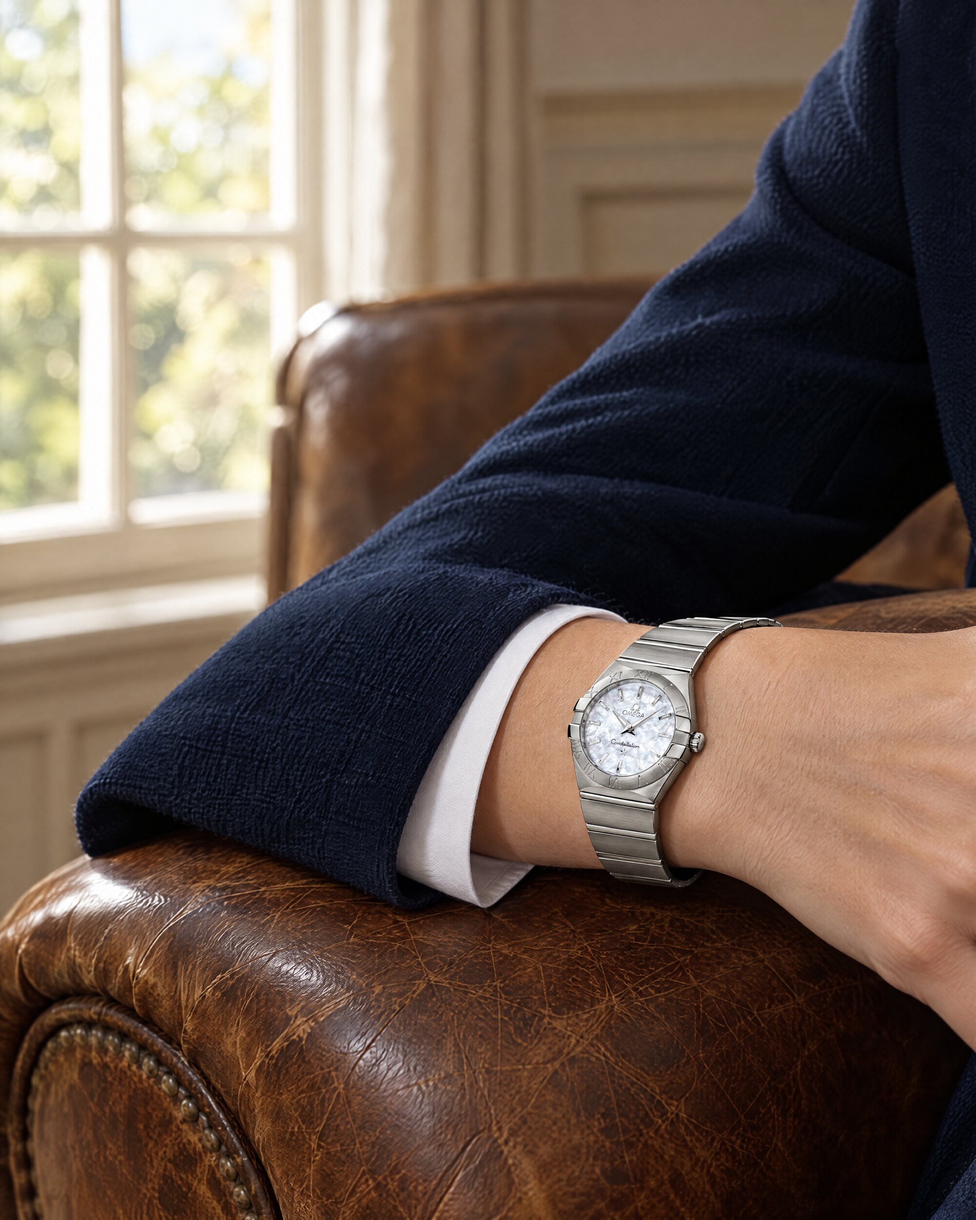 Brushed steel Constellation watch with mother-of-pearl dial on a wrist at a navy jacket cuff