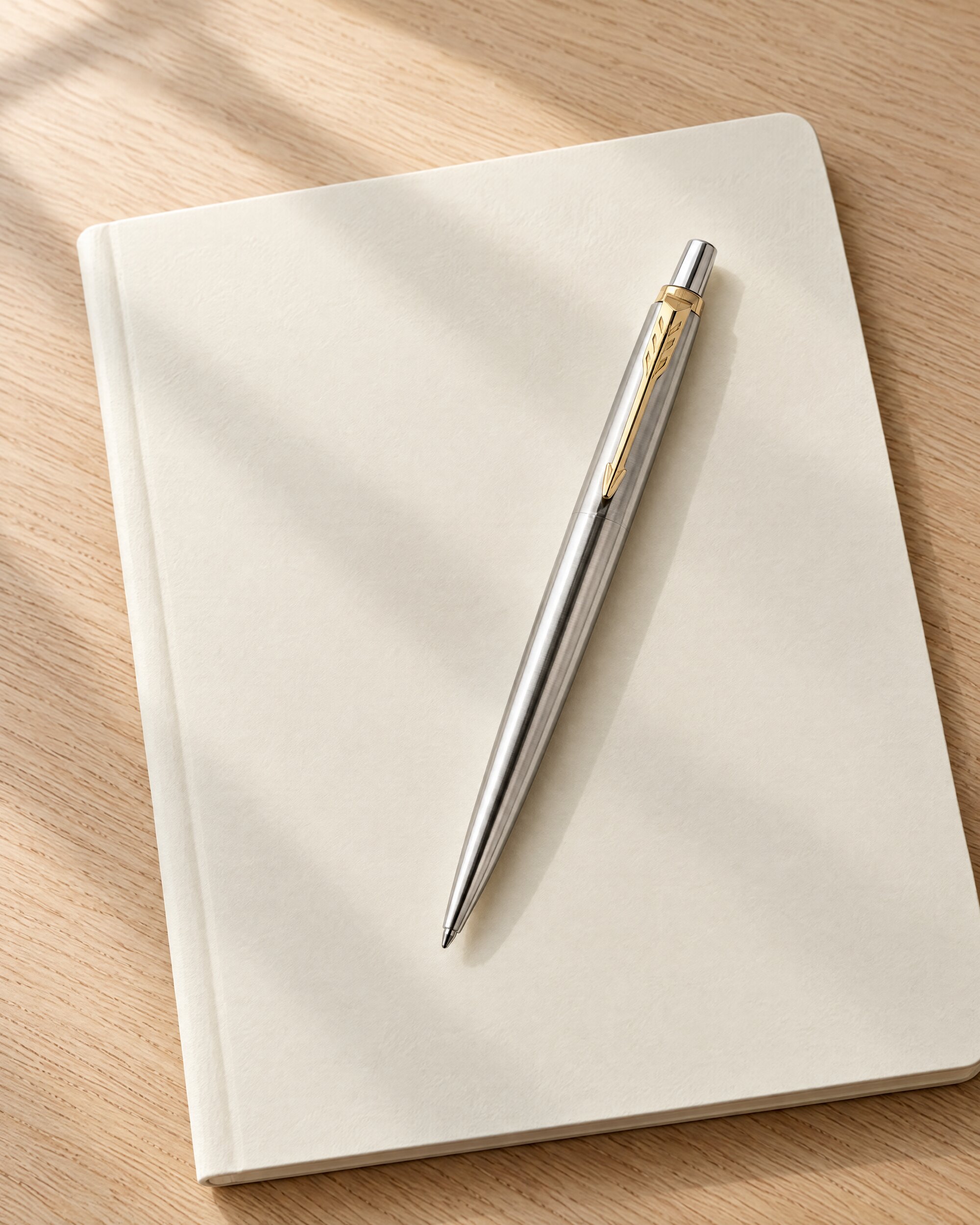 Stainless steel Parker Jotter ballpoint pen on an oak desk