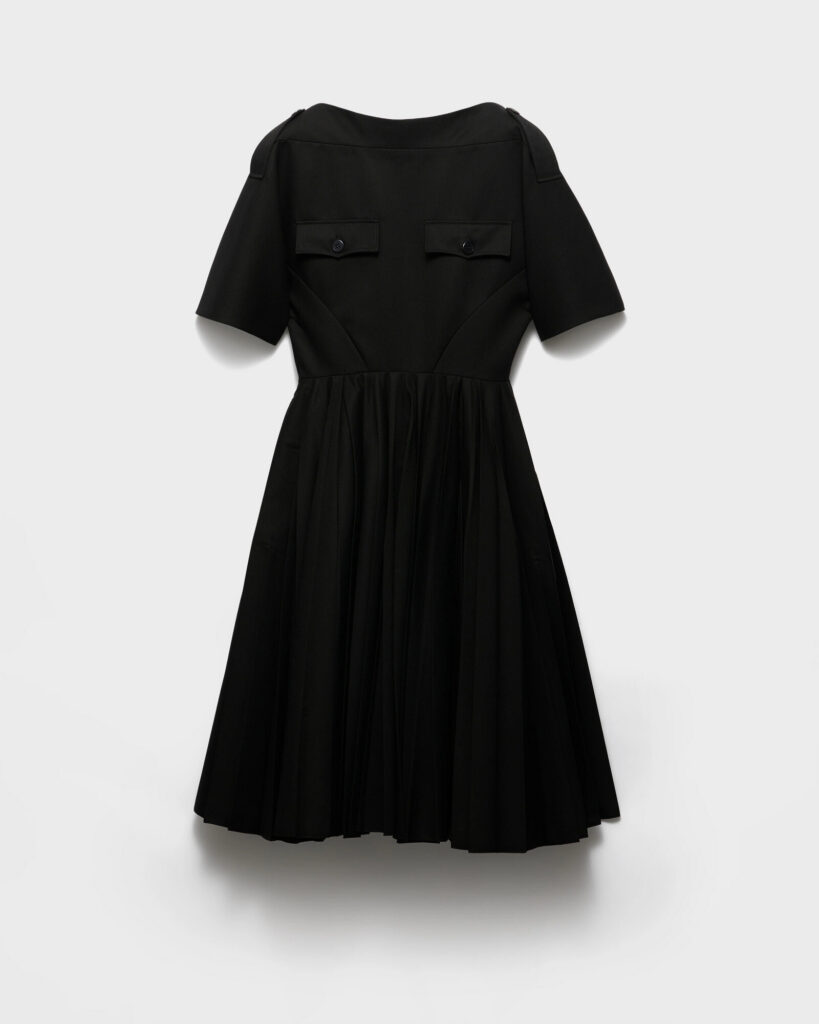 Plain black cocktail dress laid flat with black leather flats, in the spirit of the Prada black dress from Quantum of Solace
