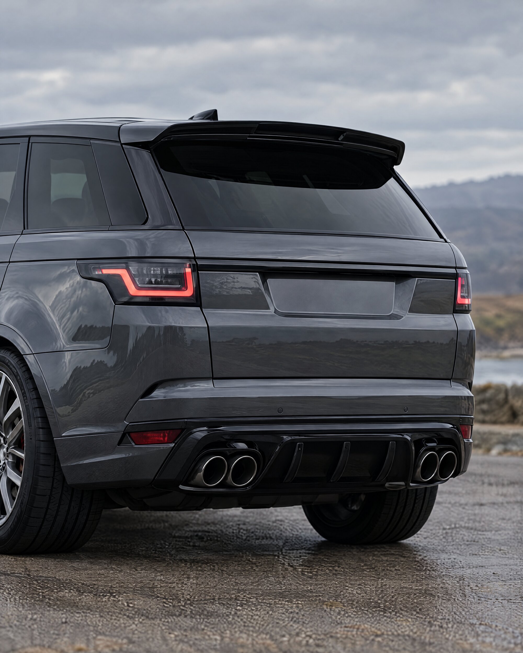 Rear detail of a dark grey Range Rover Sport SVR showing its quad tailpipes and spoiler
