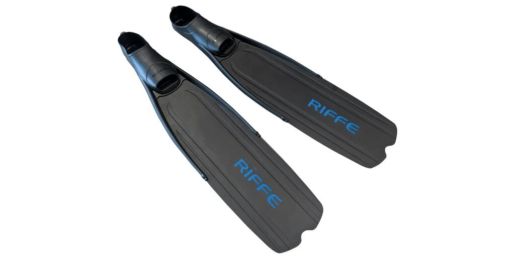 Riffe Descender long blade plastic fins lying on a weathered teak deck in soft morning light