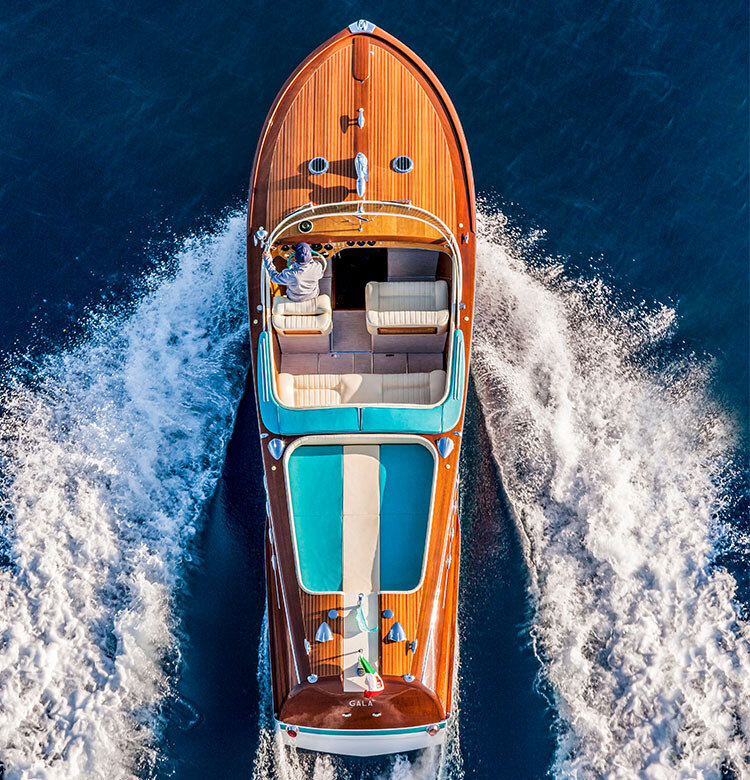 Mahogany speedboat stern with chrome cleats on glittering water