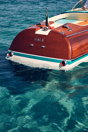 Mahogany speedboat stern with chrome cleats on glittering water