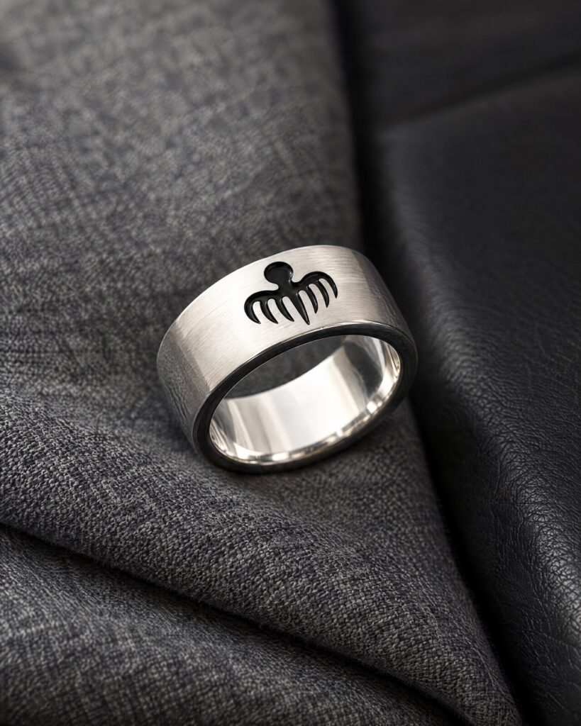 Close-up of the Spectre octopus ring in sterling silver with black enamel octopus on grey flannel