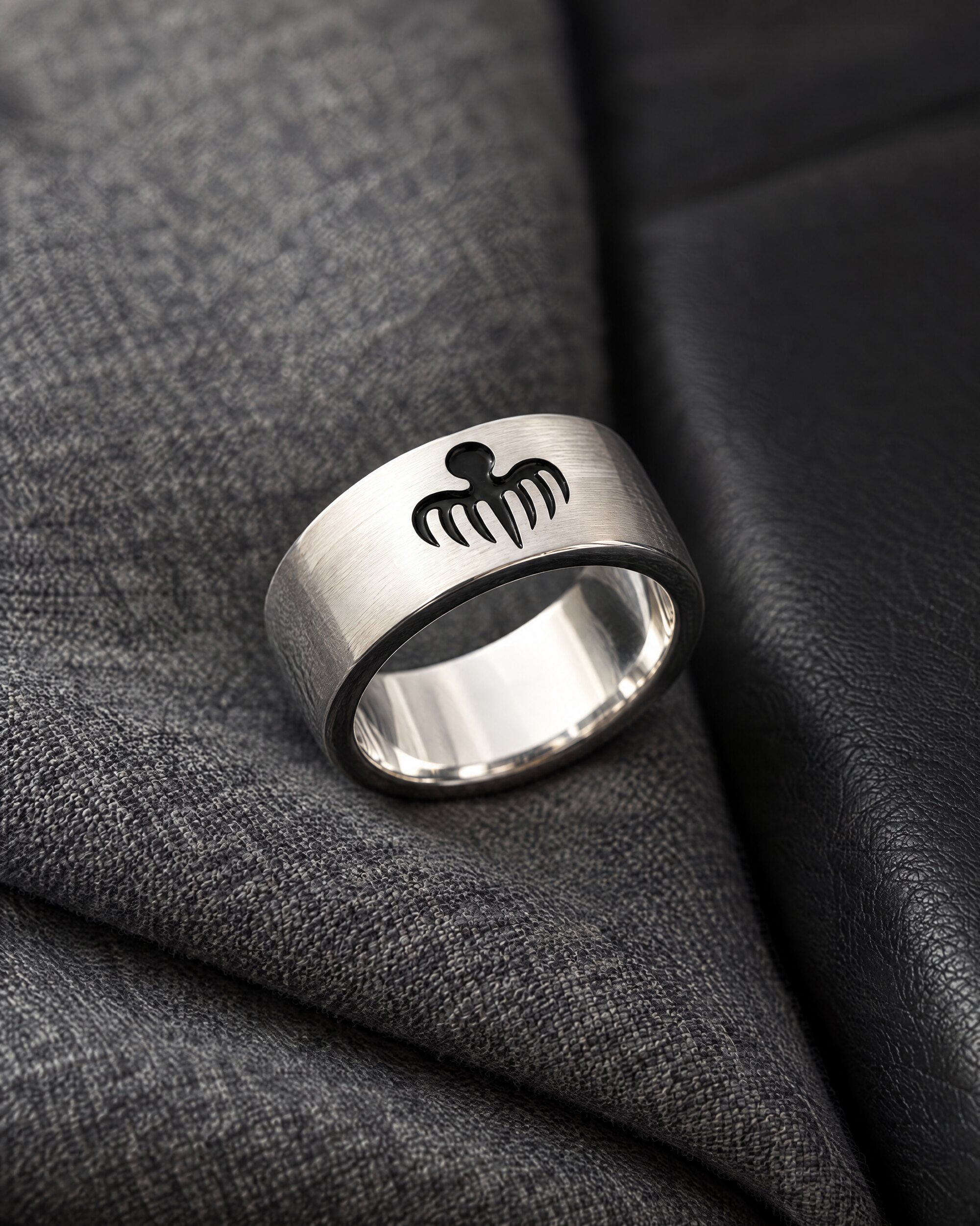 Close-up of the Spectre octopus ring in sterling silver with black enamel octopus on grey flannel