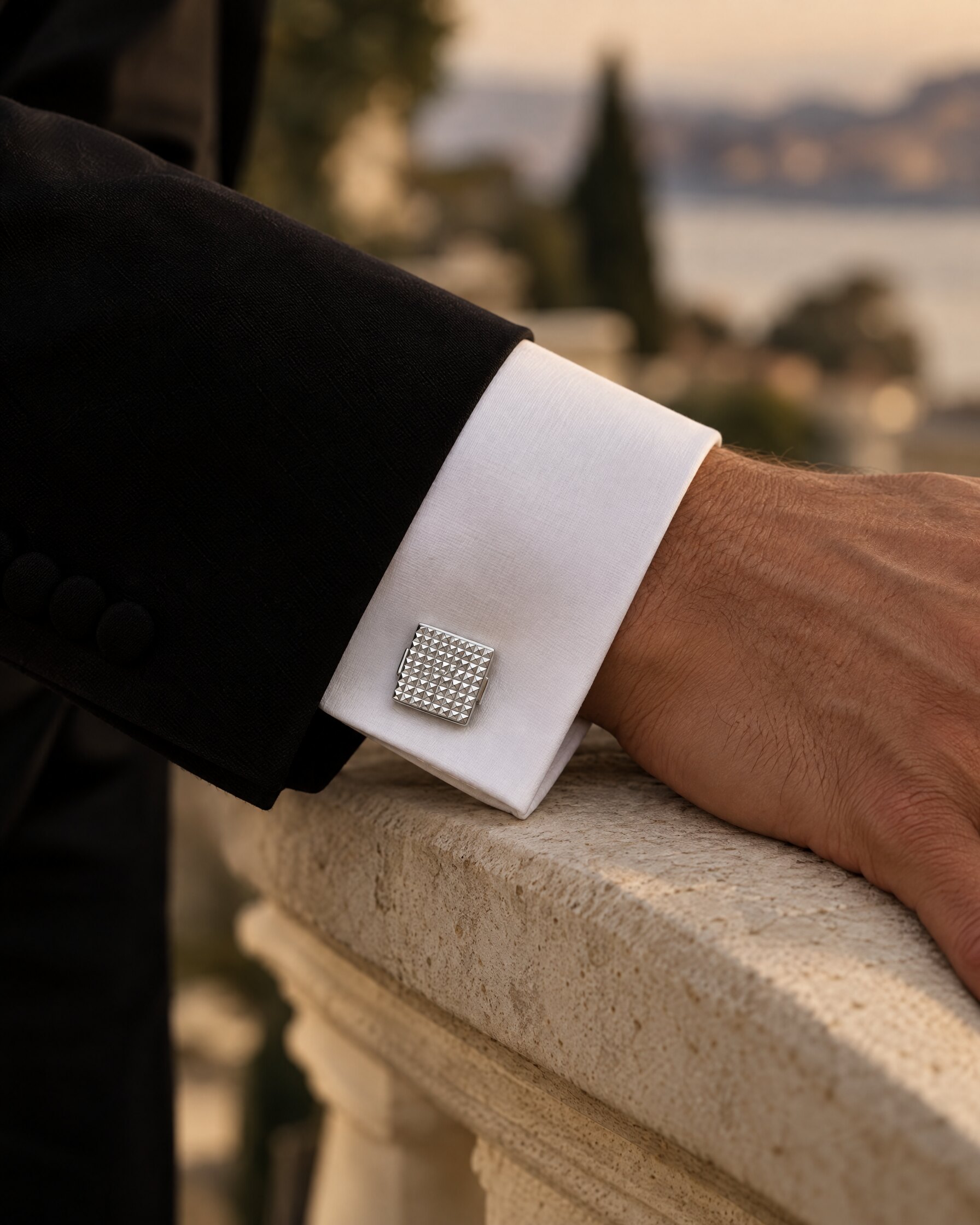 Square palladium cufflink fastening a white double cuff under a black tuxedo sleeve