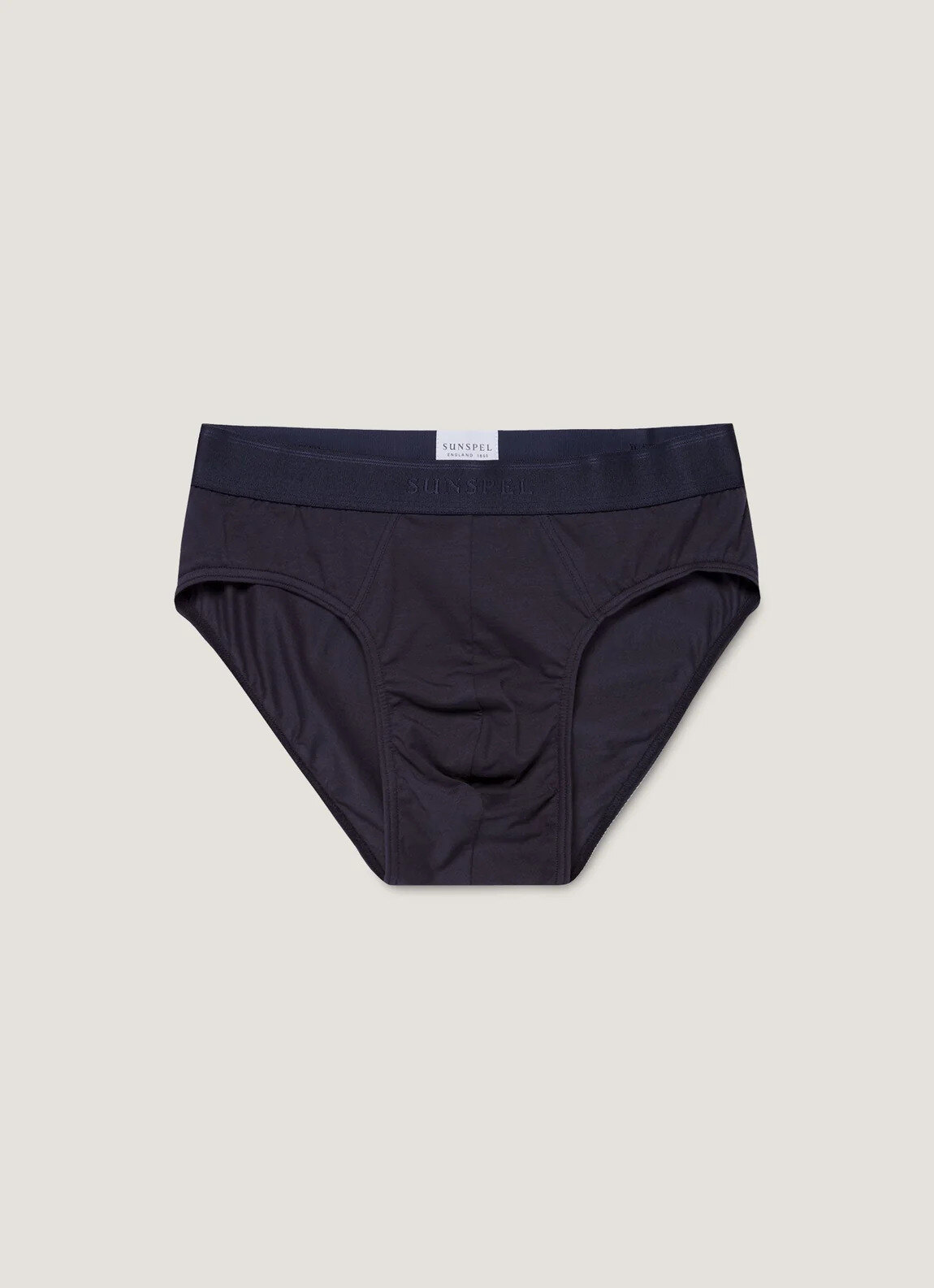 Sunspel stretch cotton brief in navy, folded on an oak surface beside a white T-shirt