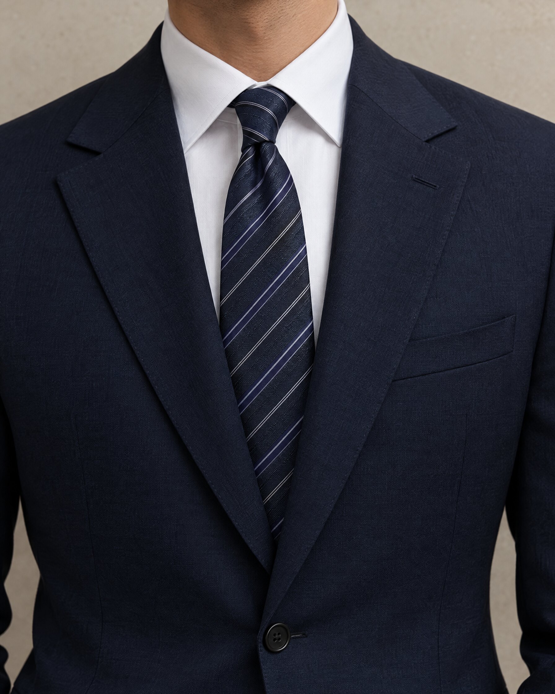 Dark blue diagonal silk tie worn with a navy suit and white shirt, face out of frame