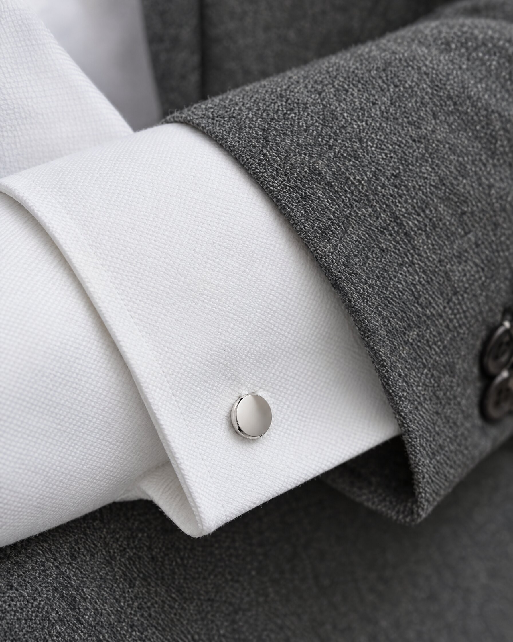 White French cuff with a plain silver cufflink under a grey suit sleeve