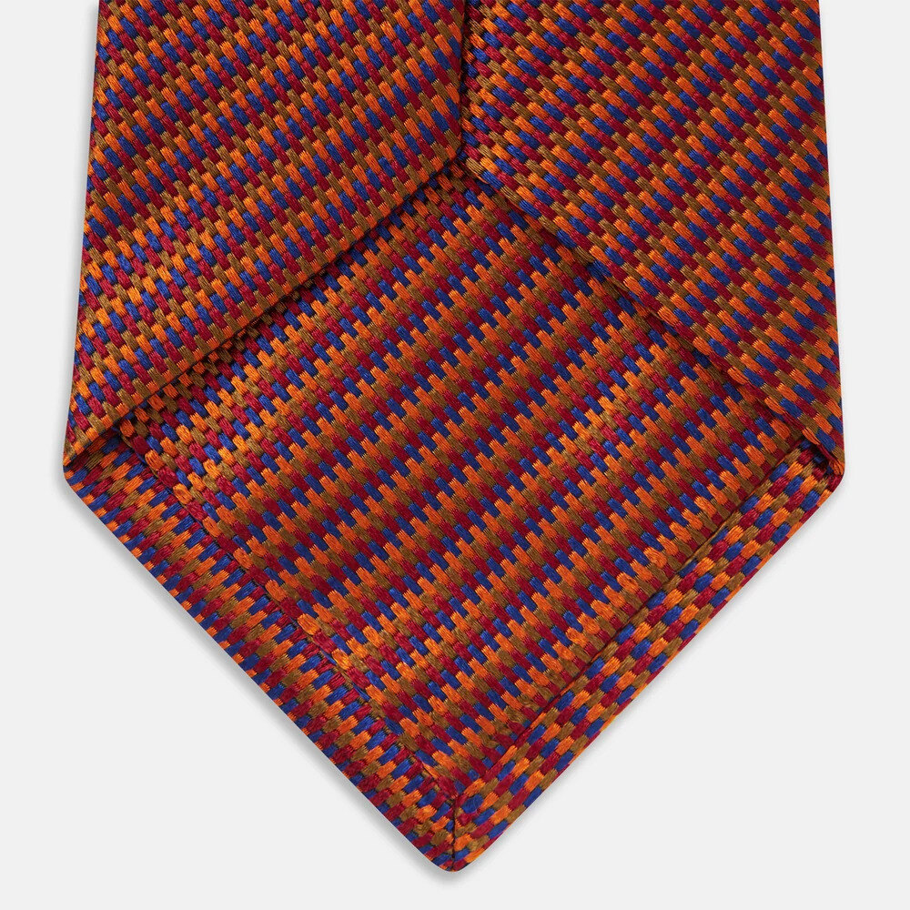 Turnbull & Asser Die Another Day silk tie in red, blue and amber beside a white shirt and charcoal jacket