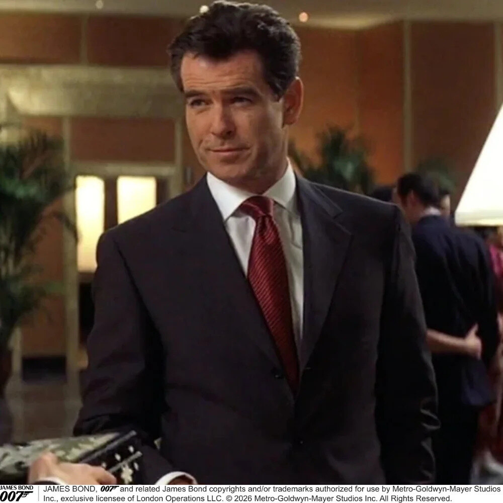 Turnbull & Asser Die Another Day silk tie in red, blue and amber beside a white shirt and charcoal jacket