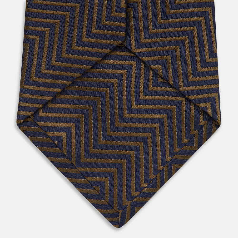 Dark silk zig zag necktie on grey linen beside a white shirt collar