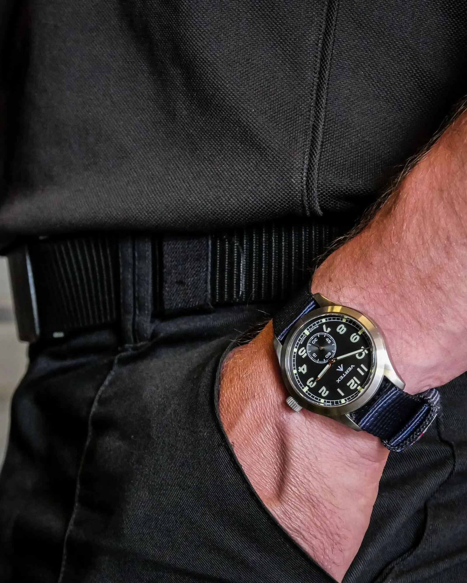 Military-style field watch on olive canvas with a brass paperweight